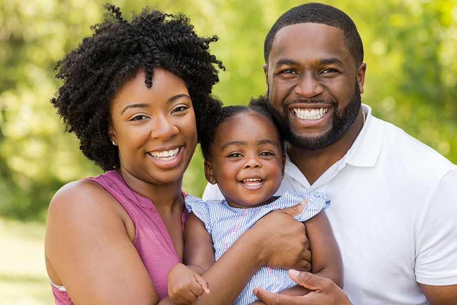 Personal Insurance - Portrait of Smiling Couple with a Toddler Standing Outside